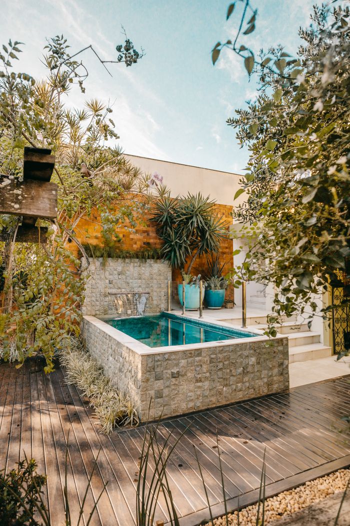 A tranquil backyard scene featuring a small pool surrounded by lush greenery, ideal for relaxation.