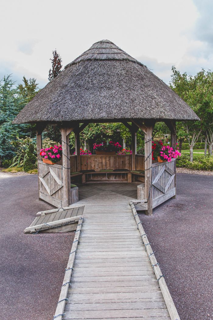 Charming wooden gazebo adorned with pink flowers in an Irish garden in Cork.