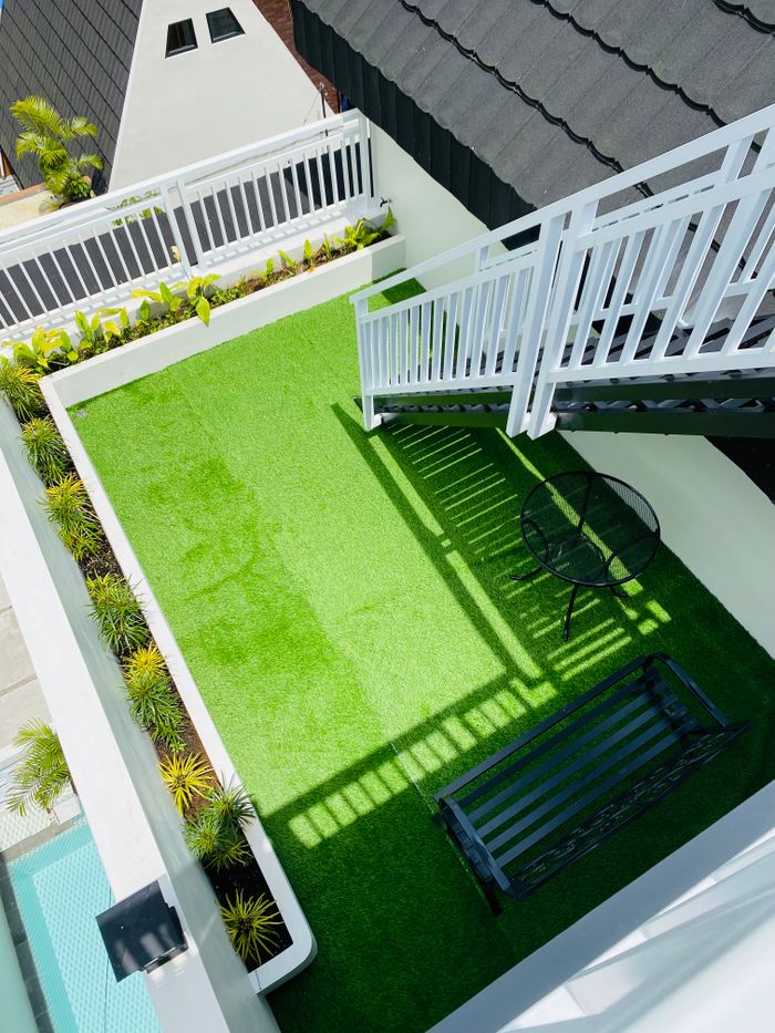 Aerial view of a stylish rooftop terrace featuring green turf and modern furniture.